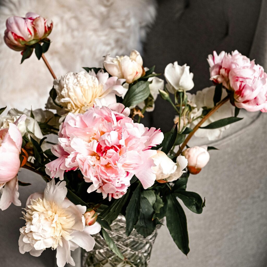 A delicate bouquet of pink and white peonies in a decorative vase, captured up close.